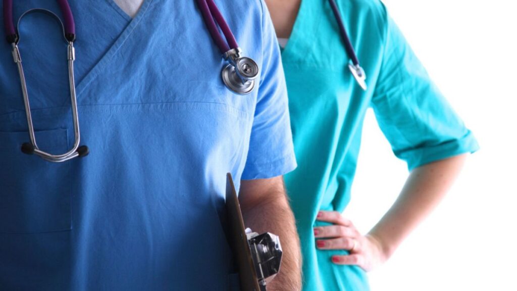 Two health workers in the UK wearing scrubs